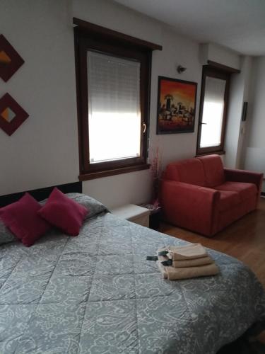 a bedroom with a bed and a red couch at Tirano in relax in Tirano