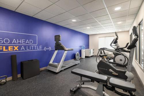 a gym with cardio machines and a blue wall at Holiday Inn Express Syracuse Airport by IHG in North Syracuse