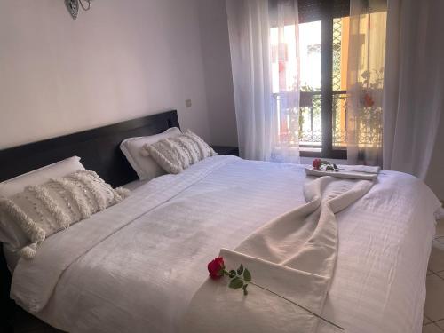 a bedroom with a white bed with a rose on it at Magnifique Appartement spacieux confort propre familial 2 chambres salon et salle a manger a 20mn a pied de place jemaa el fina 4 piscines dans espace de Golf a 12 mn en voitures l entree est gratuit pour la clientele ouvert entre 10h et 20h in Marrakech