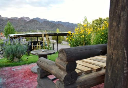 a wooden bench with a table and mountains in the background at Posada Malbec 3 Dormis in Uspallata
