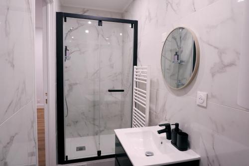une salle de bain blanche avec une douche et un lavabo dans l'établissement Cozy studio near Paris, à Maisons-Alfort