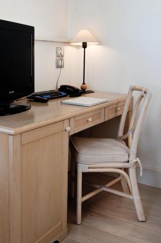 a wooden desk with a computer monitor and a chair at Hotel Sirolo in Sirolo
