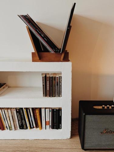 une étagère blanche avec des livres et un haut-parleur dans l'établissement Maison Marcel - Le Four à Pain, à Rosporden