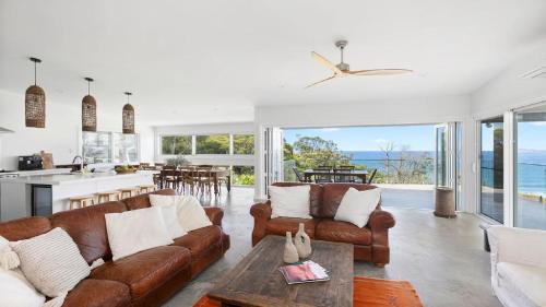 a living room with leather couches and a table at Stunning Ocean Views and Pool in Hardys Bay