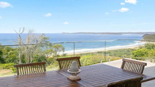 a wooden table with two chairs and a view of the ocean at Stunning Ocean Views and Pool in Hardys Bay