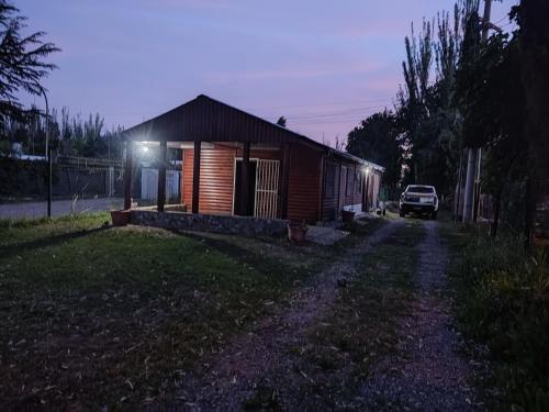 a small wooden cabin with a car parked next to it at Cabaña DON LITO in Ciudad Lujan de Cuyo