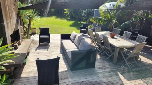 a patio with a couch and a table and chairs at Beachfront Sunset Bach in Piha