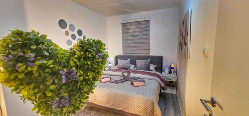 a bedroom with a bed with a large green plant at Villa White Pearl Buna in Hodbina