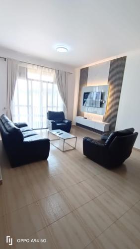 a living room with two couches and a tv at Scenic Serenity at Pearl Marina in Entebbe