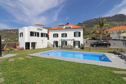 a white house with a swimming pool in front of it at Casa das Rosas e Casa Do Mar in Arco da Calheta