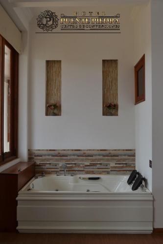 a bath tub in a room with a sign on the wall at Hotel PUENTE PIEDRA PARK in Villa de Leyva