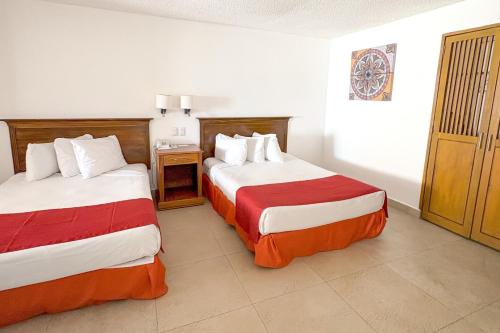 a hotel room with two beds with red and white sheets at Spacious, comfortable, and with beach access! in Puerto Vallarta