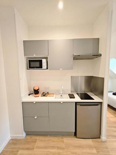 une petite cuisine avec un évier et un micro-ondes dans l'établissement Studio tout confort Châtel Guyon, à Châtel-Guyon