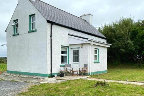 a small white house with a table and chairs outside at 3br-Sea View-Fireplace-Garden-Free Parking in Falcarragh