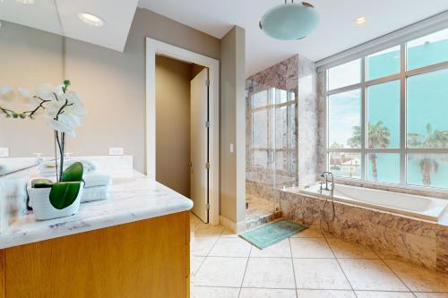 Un baño con bañera y una gran ventana. en Sapphire Bungalow #106, en South Padre Island