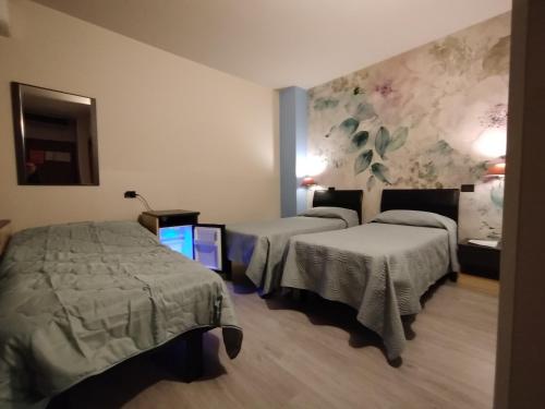 a hotel room with two beds and a tv at Hotel Milano San Giovanni Lupatoto in San Giovanni Lupatoto