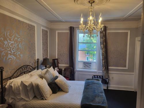 a bedroom with a bed and a chandelier and a window at The Tamworth Hotel, Tamworth ,Ontario, Canada in Tamworth