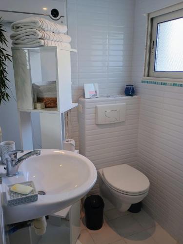 une salle de bain blanche avec un lavabo et des toilettes dans l'établissement Logement privé à 50m des plages, à Gâvres