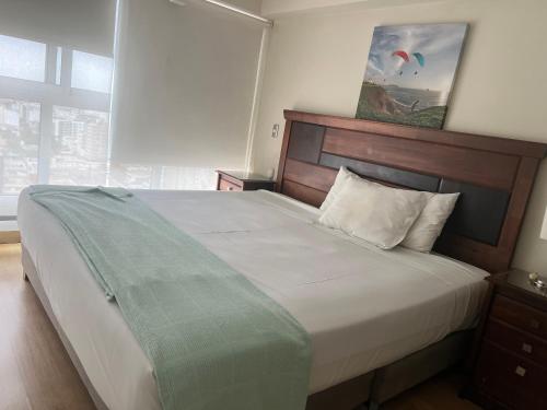 a bedroom with a large bed with a wooden headboard at Urbano Apartments in Lima