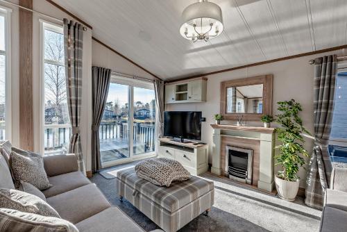 ein Wohnzimmer mit einem Sofa, einem TV und einem Kamin in der Unterkunft Kingfisher Lodge - Lakeside Lodge With Hot Tub in Woodhall Spa