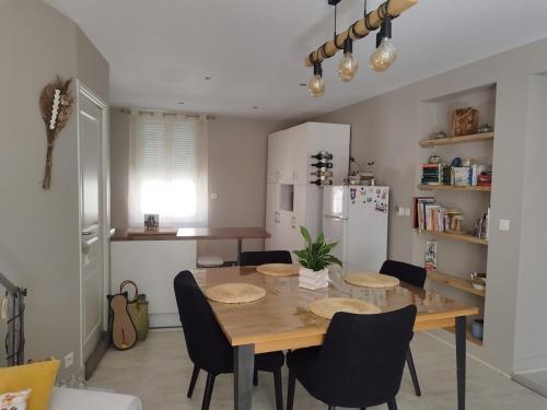 une salle à manger avec une table et des chaises et une cuisine dans l'établissement Charmant appartement Le Coteau - Roanne, à Le Coteau