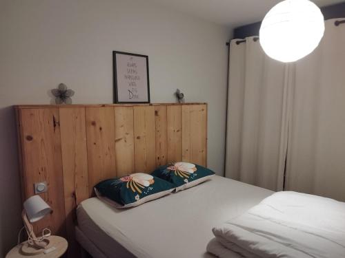 une chambre avec un lit avec une tête de lit en bois dans l'établissement Charmant appartement Le Coteau - Roanne, à Le Coteau