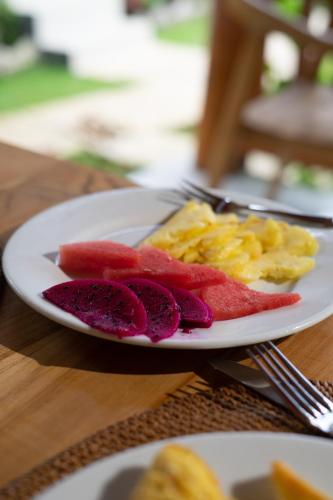 une assiette de nourriture avec des fruits et des œufs sur une table dans l'établissement Nusa Dewata Cottage, à Nusa Penida