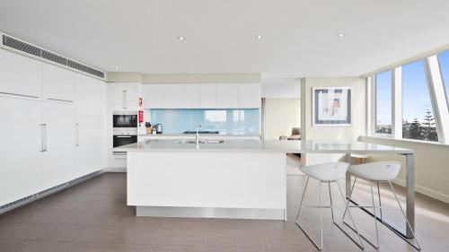 a kitchen with white cabinets and a counter with stools at Bayview 504 in Mandurah