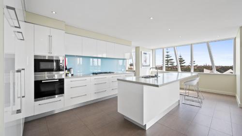 a kitchen with white cabinets and a large window at Bayview 504 in Mandurah