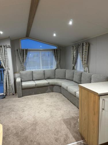 a living room with a gray couch in front of a window at Willerby Castleton,Camber Sands- sleeps 6 Entertainment passes not included in Camber