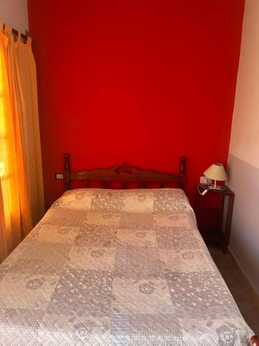 a bedroom with a bed with a red wall at La Churita 2 - EL GUALICHO HOSTAL in Humahuaca