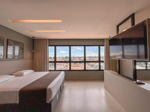 a bedroom with a large bed and a large window at O Melhor Flat de Campo Grande in Campo Grande