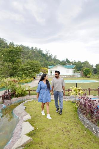 a man and woman walking through a garden at Mount Edge Riverside Hotel in Bandarawela