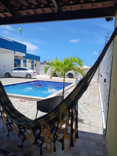 a hammock in front of a swimming pool at Flat Brisa do Mar in Pitimbu