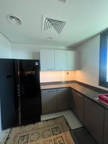 an empty kitchen with a black refrigerator in it at Apartment Almouj Lagoon in Muscat