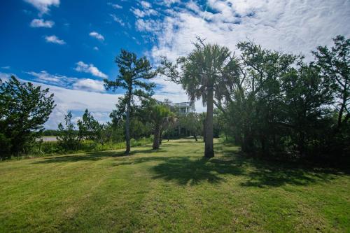 a field with trees and a house in the background at Tequila Sunset in Edisto Island