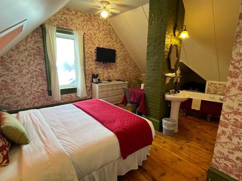 a bedroom with a bed and a bathroom with a sink at La Belle Victorienne in Magog-Orford