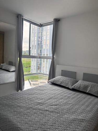 a bedroom with a bed and a large window at Apartamento Turistico Monte Azul in Armenia