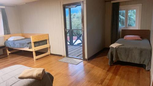 a room with two beds and a door to a balcony at Hostal La Casona Ensenada con parking in Ensenada
