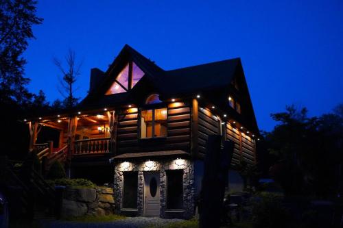 a wooden house with lights on it at night at Cozy Catskill Log Home in Monticello