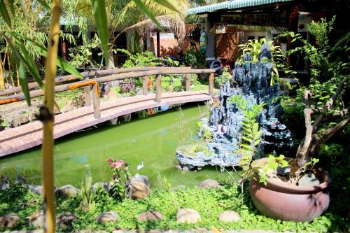 a bridge over a pond with a fountain in a garden at Hoang Nga Garden Guesthouse in Mui Ne