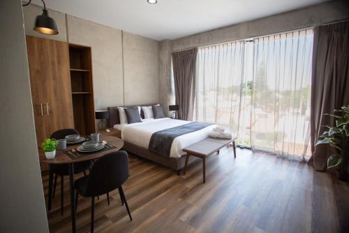 a hotel room with a bed and a table with a tableablish at Suites del Carmen Consulado in Guadalajara