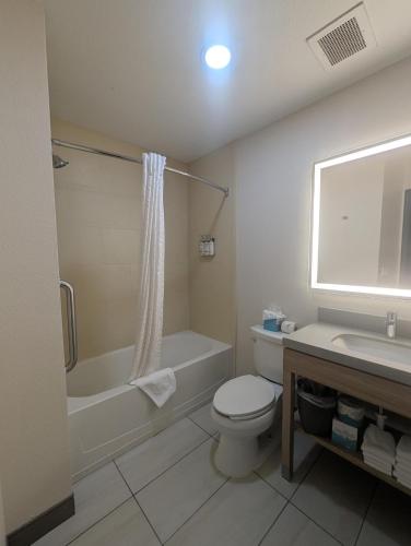 a bathroom with a toilet and a tub and a sink at Candlewood Suites Loveland by IHG in Loveland