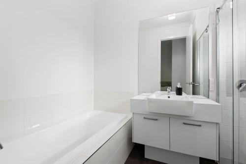 a white bathroom with a sink and a tub at Latte's Nest in Point Lonsdale