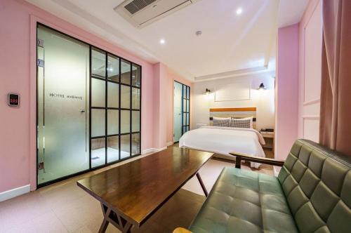 オサンにあるAvenue Hotelのベッドとソファとテーブルのある部屋