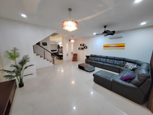 a living room with a black leather couch and a staircase at Triple Z Homestay Kuching - LANDED 14 PAX in Kuching