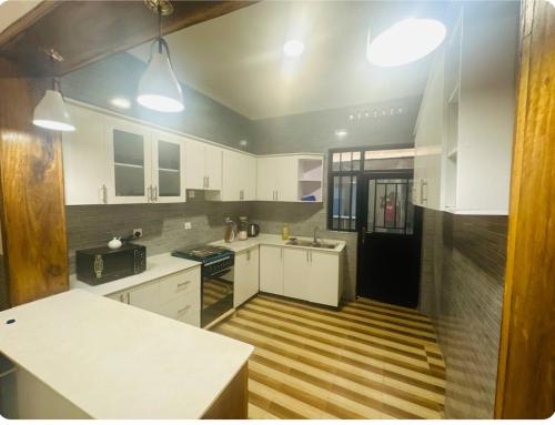 a kitchen with white cabinets and a black refrigerator at Brand new house in Kigali