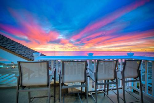 a group of chairs sitting at a bar with a sunset at 3636 Carlsbad Blvd - Upper in Carlsbad