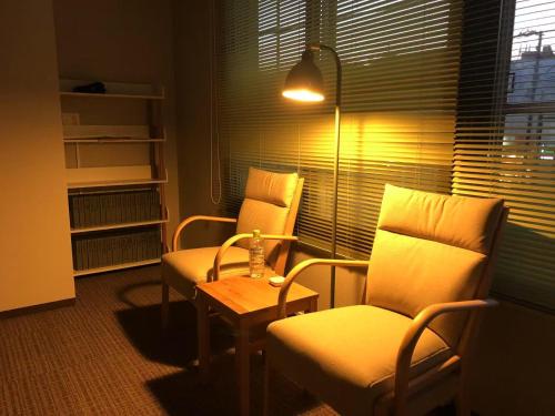 ein Zimmer mit zwei Stühlen und einem Tisch und einer Lampe in der Unterkunft ForYou Honancho 方南町 in Tokio