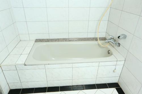 a bath tub in a tiled bathroom with a hose at Banciaoking Hotel in Taipei